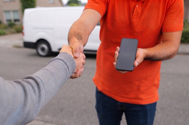 Illustration of a technician handing a finished phone back to a customer across a repair mat.